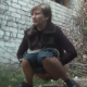 An Eastern-European girl pees outdoors in a public area.